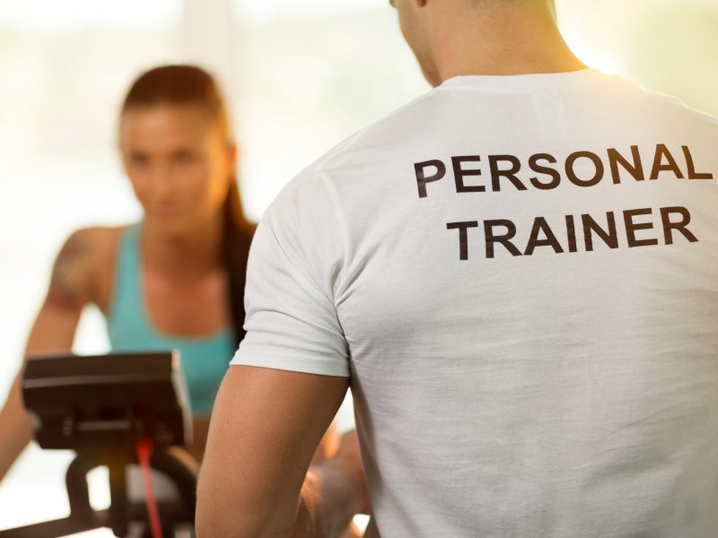 Personal trainer with his client woman on cycling machine at the gym